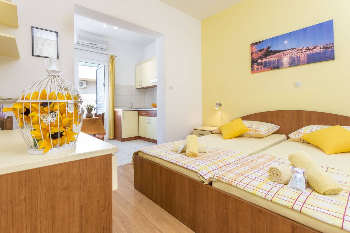 Ein Hotelzimmer mit Bett, Nachttisch, einem Bild an der Wand und Blick aufs Meer.