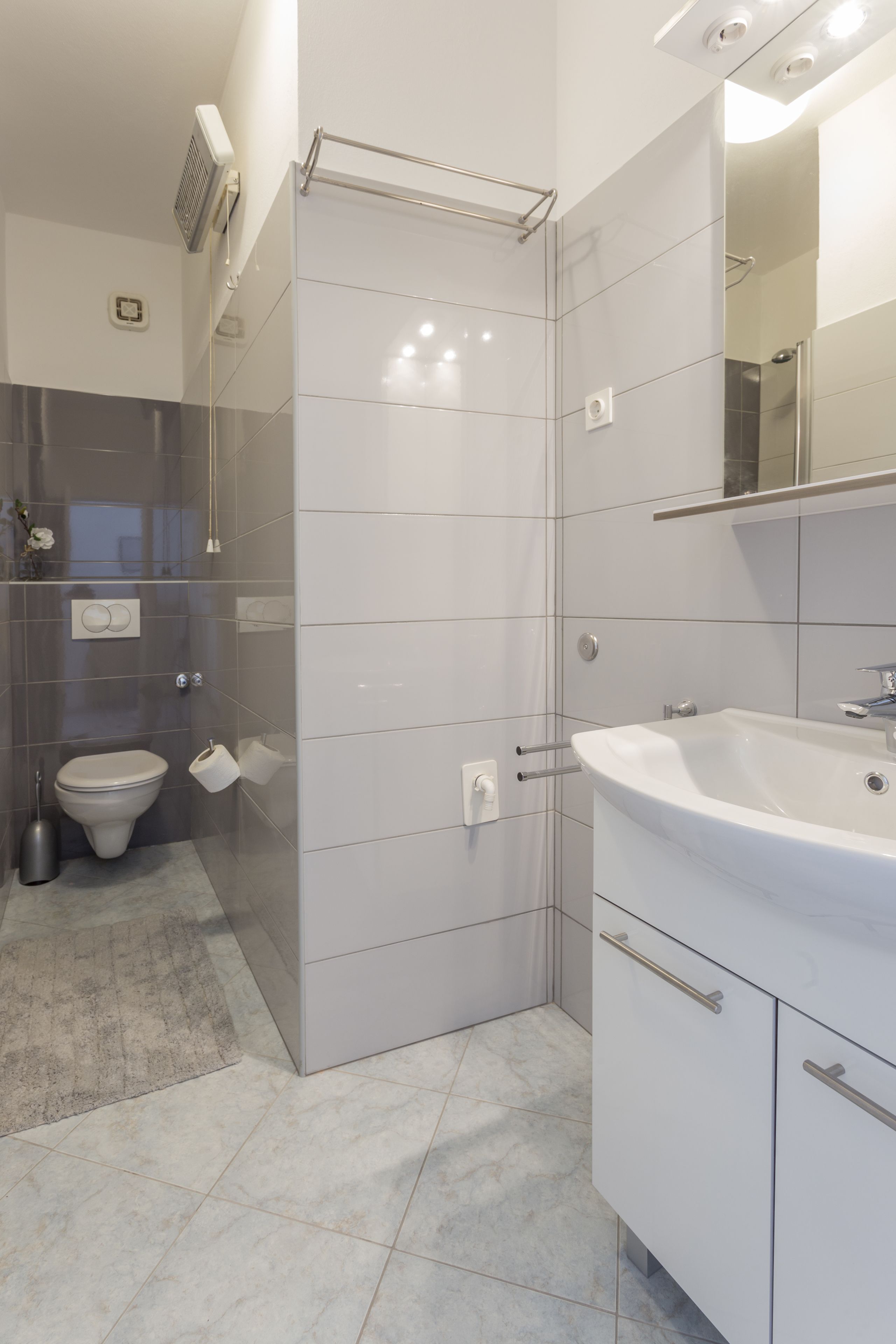 A modern bathroom with a toilet, sink, and shower.