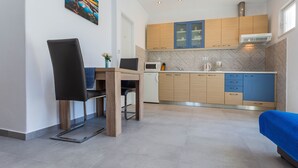 A compact kitchen with wooden cabinets, a microwave, and a coffee machine. - Apartmani Ivanovic (Hvar)