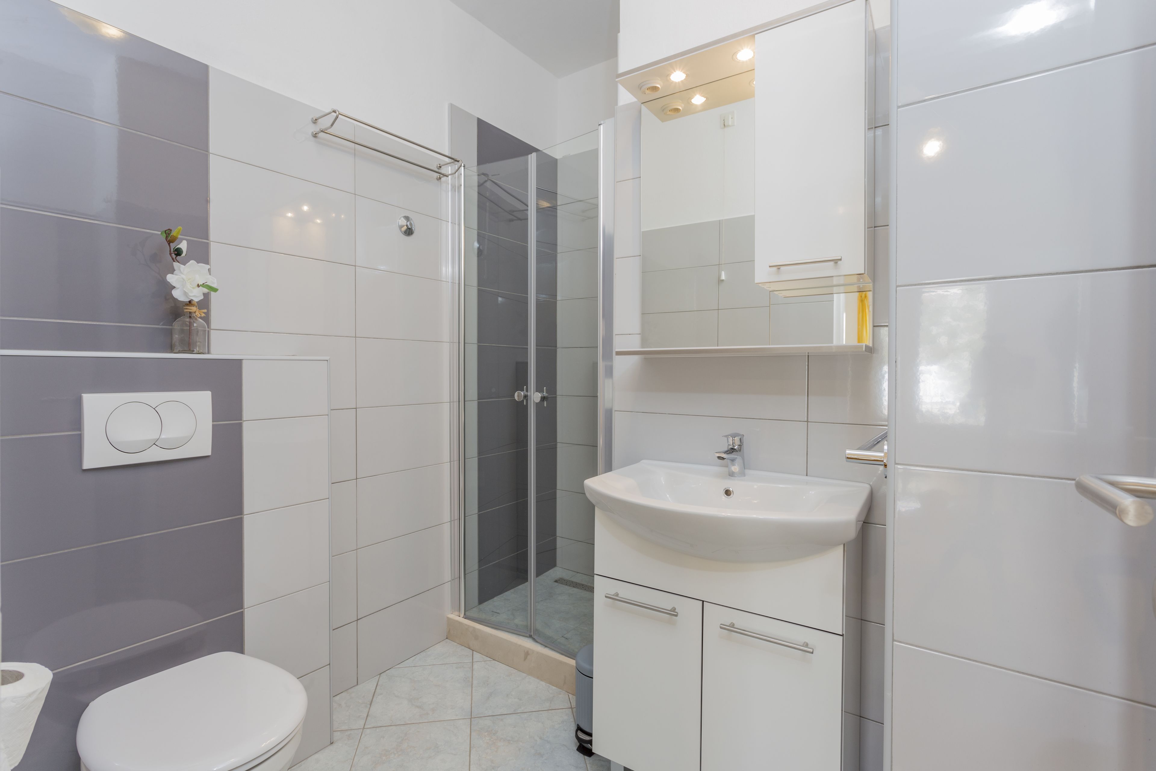 Un baño moderno con inodoro, lavamanos y cabina de ducha de vidrio.
