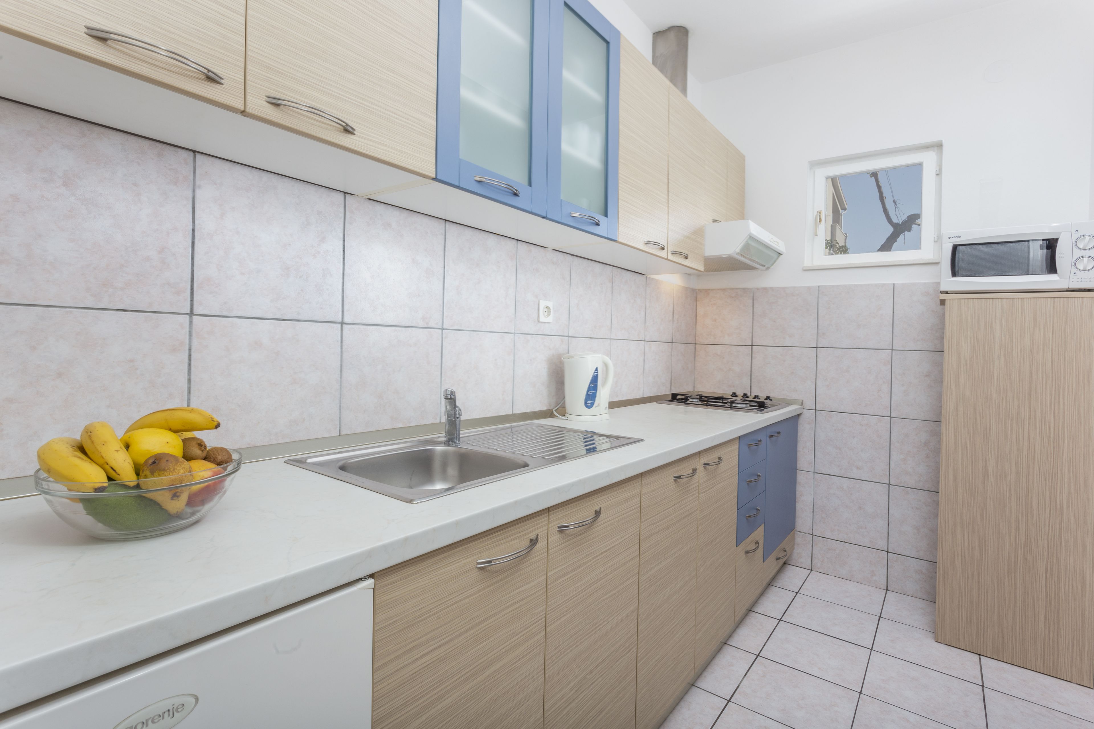 Una cucina moderna con piano di lavoro bianco, lavello, fornello e pensili.