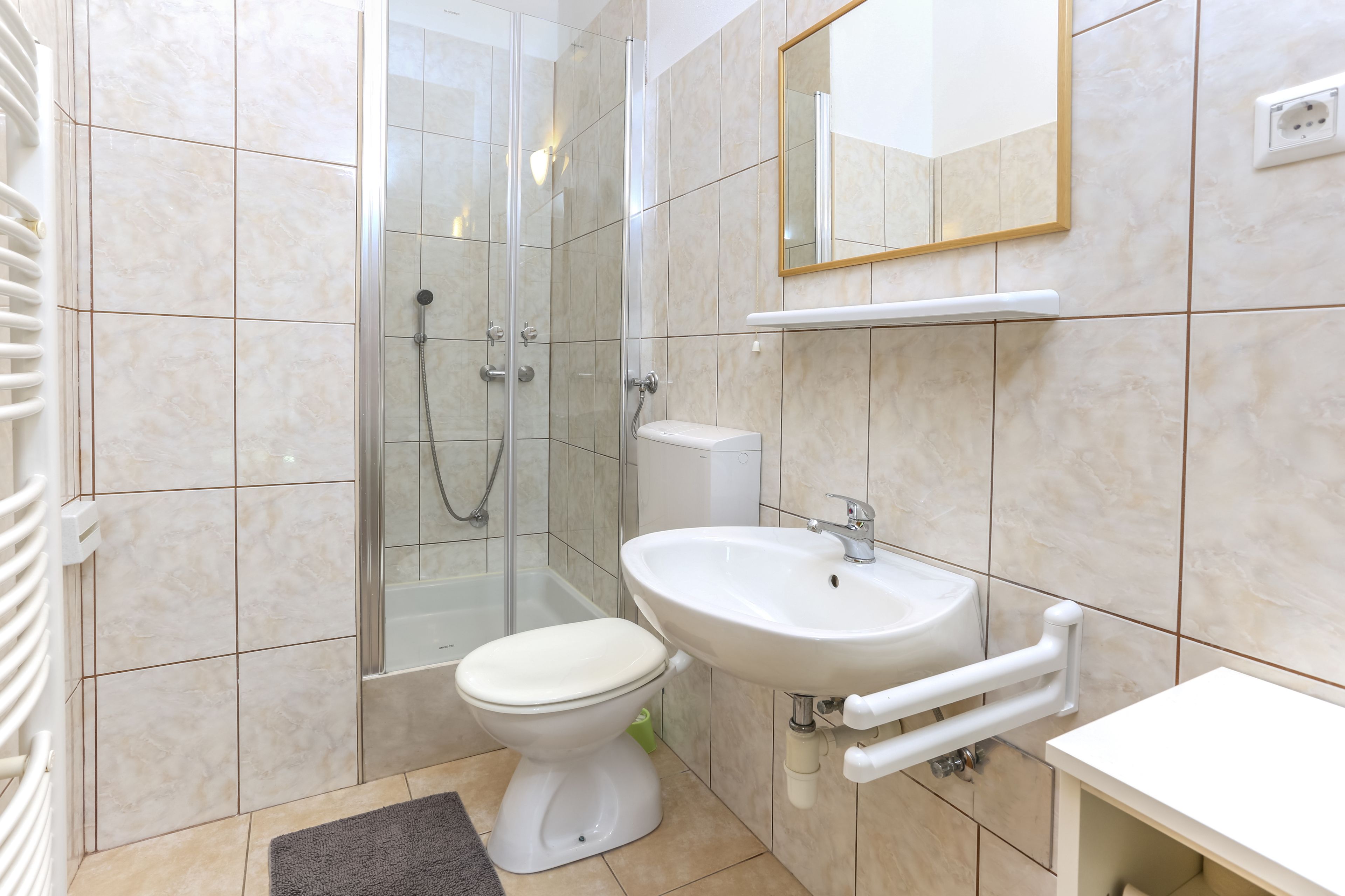 A bathroom with a shower, toilet, sink, and mirror.