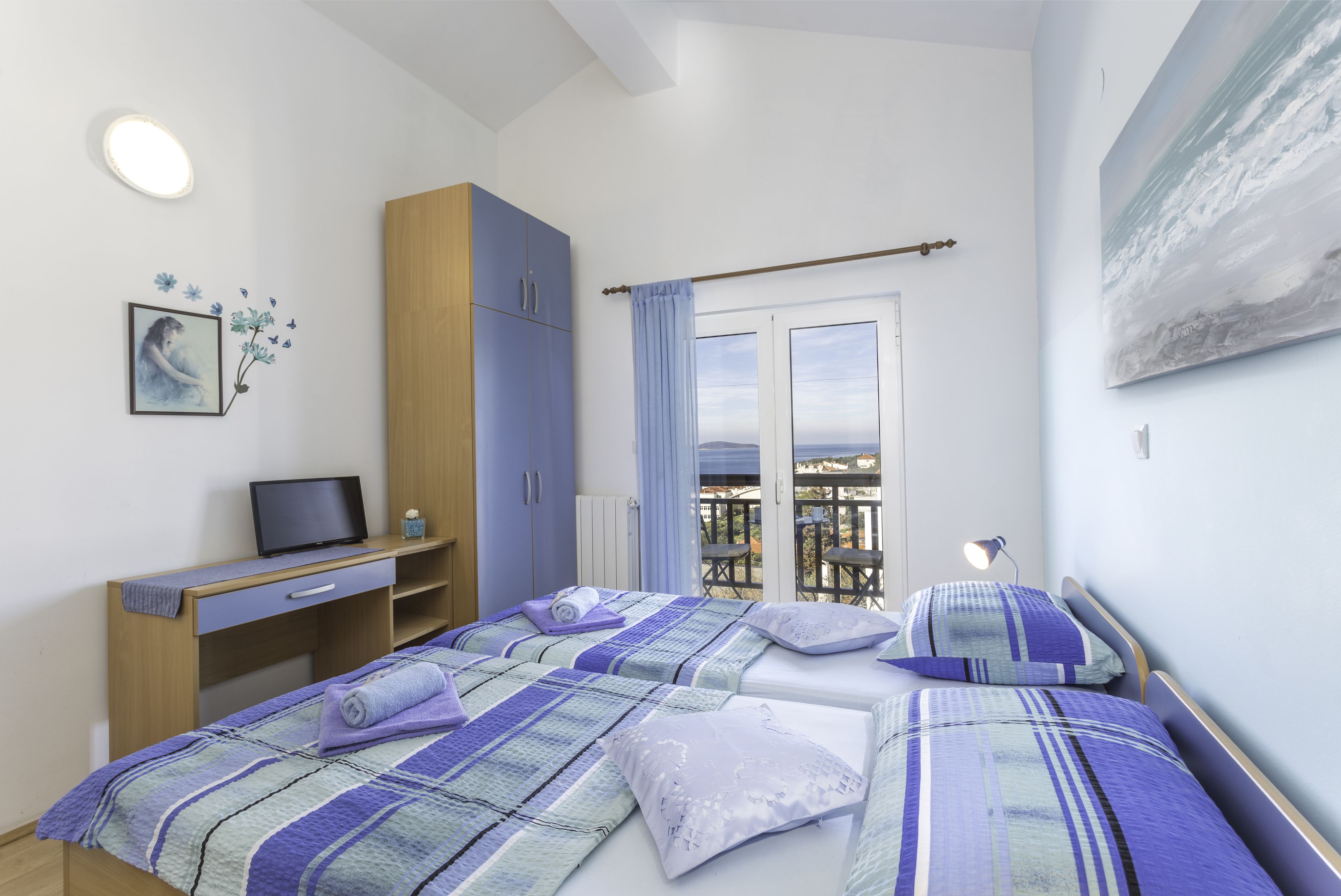 A bedroom with a bed, a desk, a chair, a wardrobe, and a window with a view.