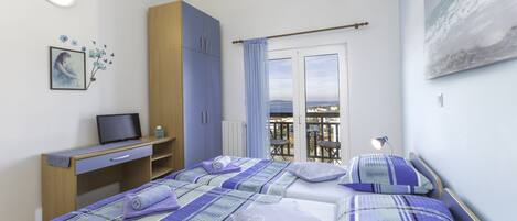 A bedroom with a bed, a desk, a chair, a wardrobe, and a window with a view.