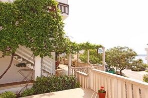 A balcony with a pergola, a staircase, and a sign indicating 'Rooms Apartments'. - Apartmani Ivanovic (Hvar)