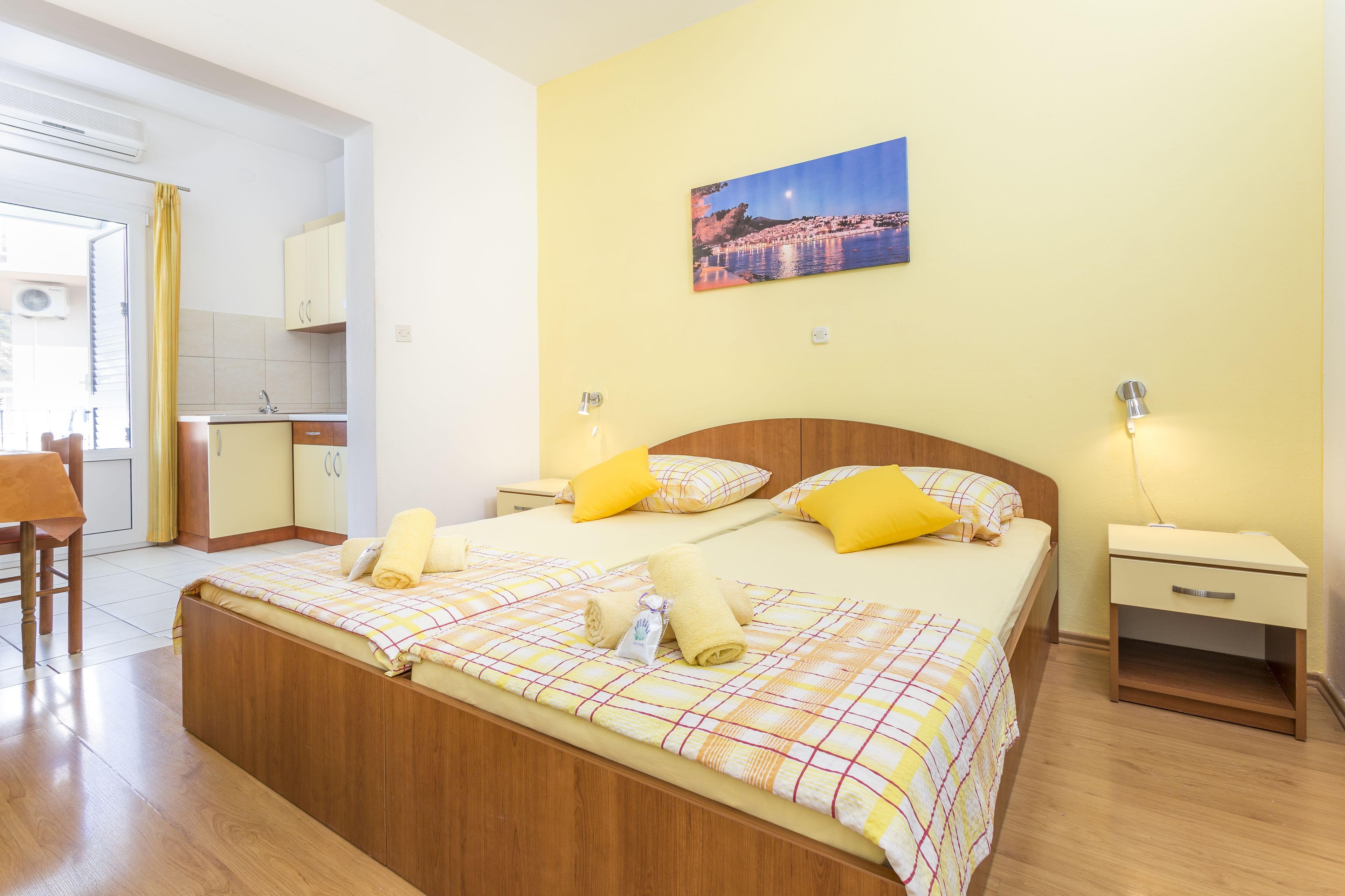 Une chambre d’hôtel avec un lit, des tables de chevet, une commode, un tableau au mur et une vue sur l’extérieur.
