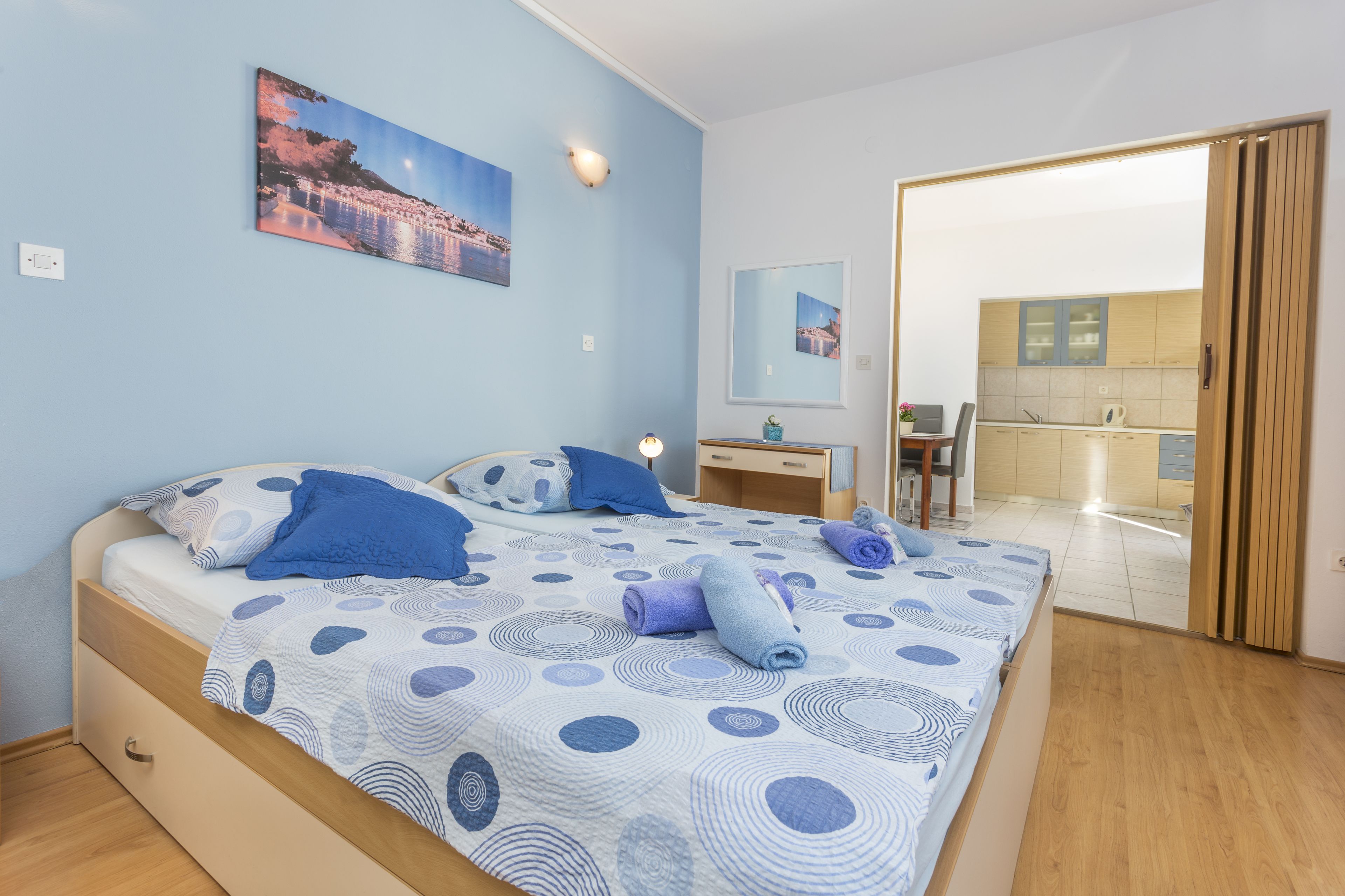 Un dormitorio con cama, mesita de noche, espejo y vistas al baño.