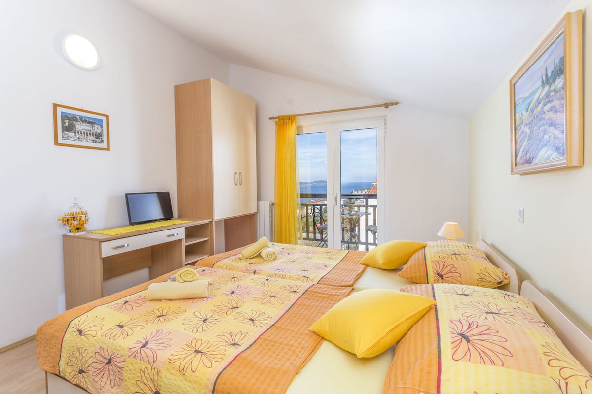 Ein Schlafzimmer mit einem Bett, einem Schreibtisch, einem Computer und einem Fenster mit Blick.
