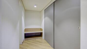 A narrow hallway with a wooden bench, a grey sliding door, and a recessed ceiling light.