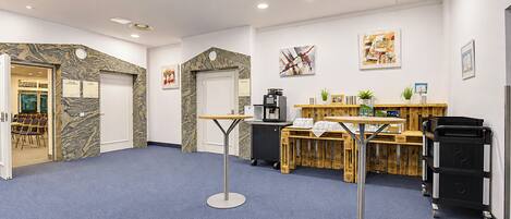 A reception area with a coffee machine, a counter, and a seating area with chairs.
