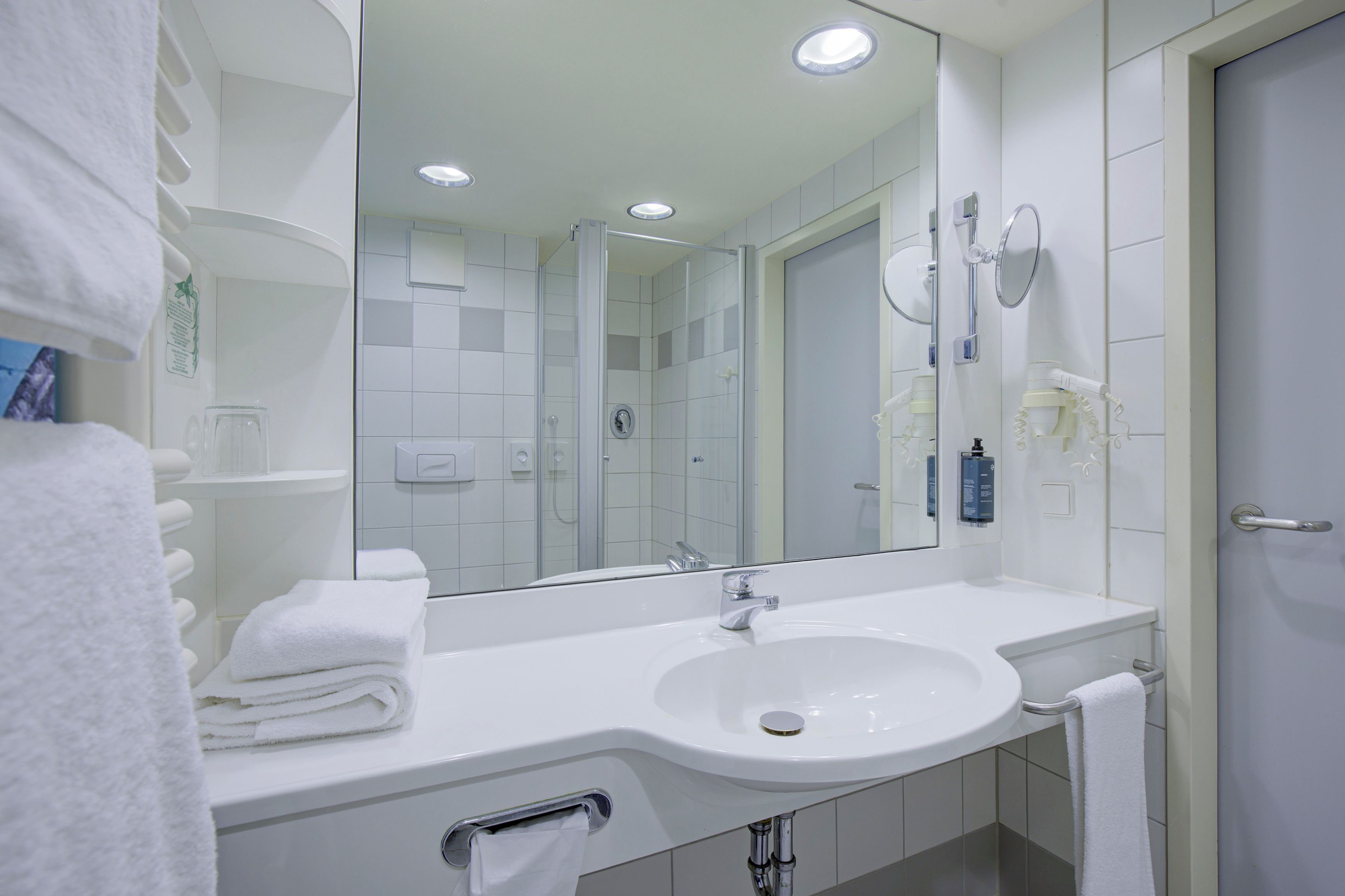 Ein modernes Badezimmer mit Waschbecken, Spiegel und Handtuchhalter.