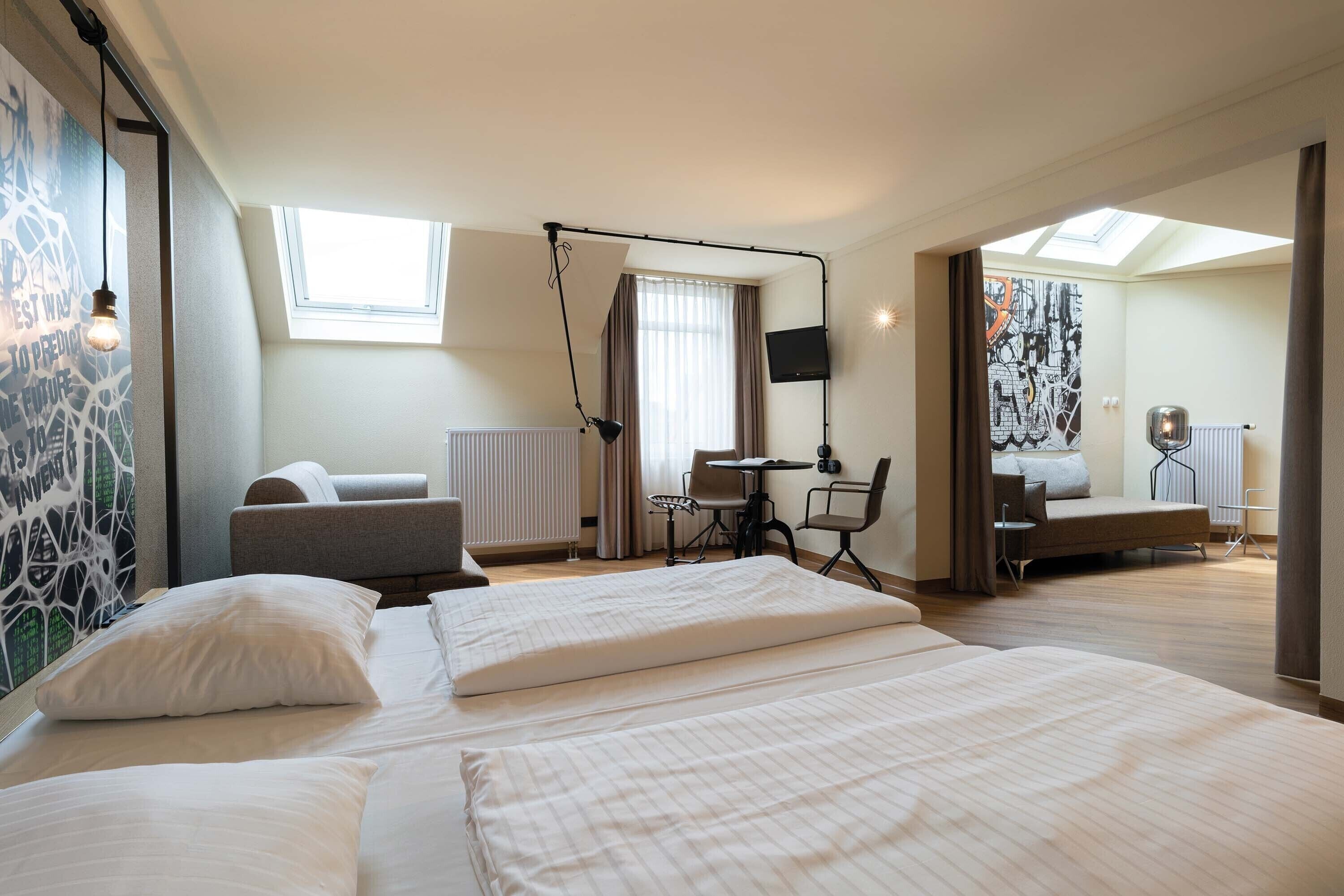 A hotel room with two beds, a desk, a chair, a TV, and a large window.