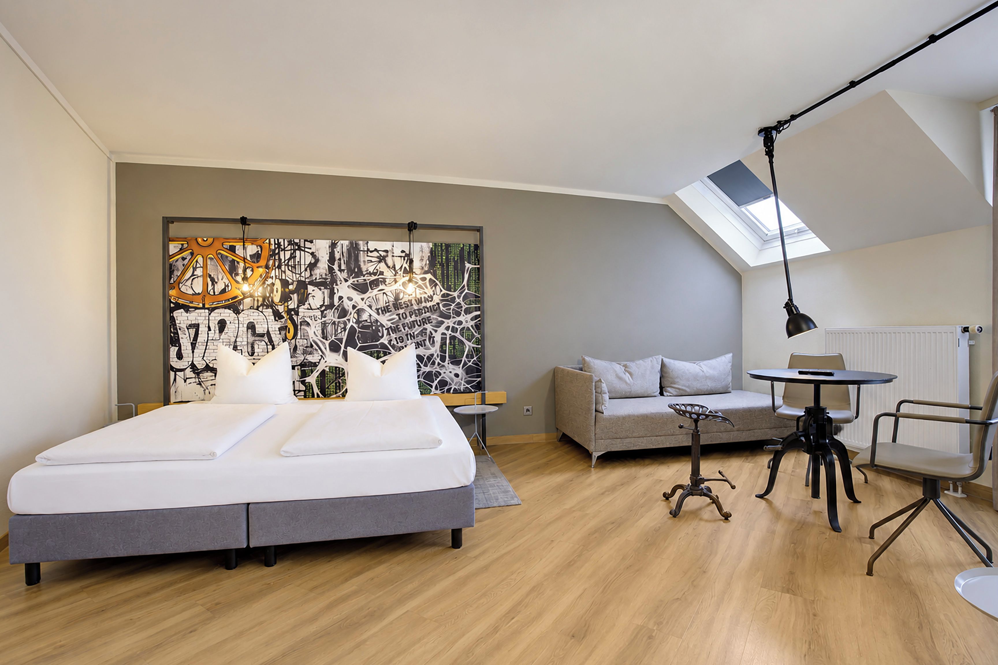 Un dormitorio moderno con una cama grande, un sofá, un escritorio con una silla y un tragaluz.