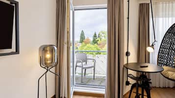 A room with a balcony, a table, a chair, and a floor lamp.