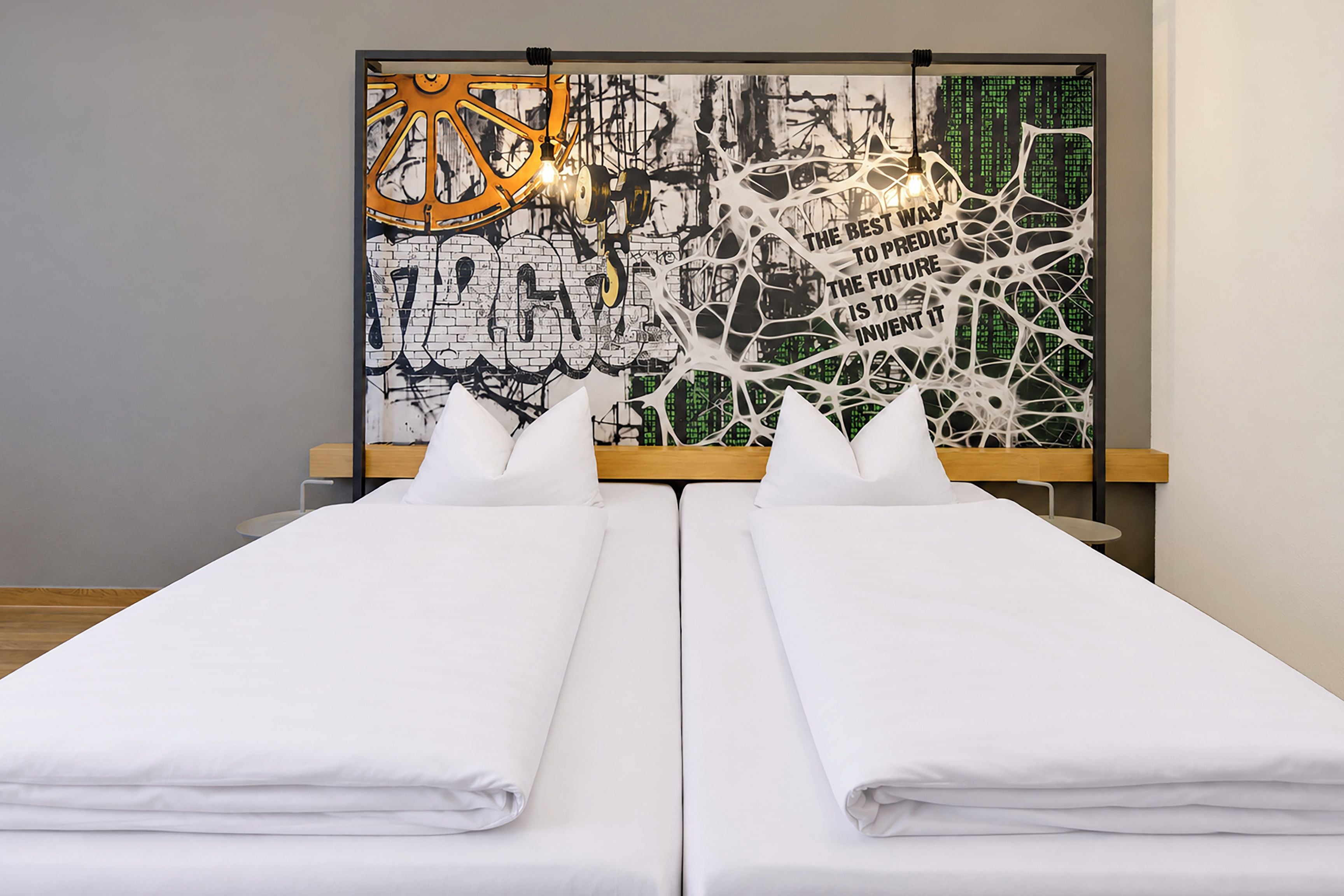 A double bed with white linens in a room with a modern design, featuring a wall art piece with abstract and graffiti elements.