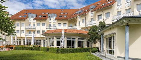 A multi-story hotel with a red-tiled roof, large windows, and a well-maintained lawn.