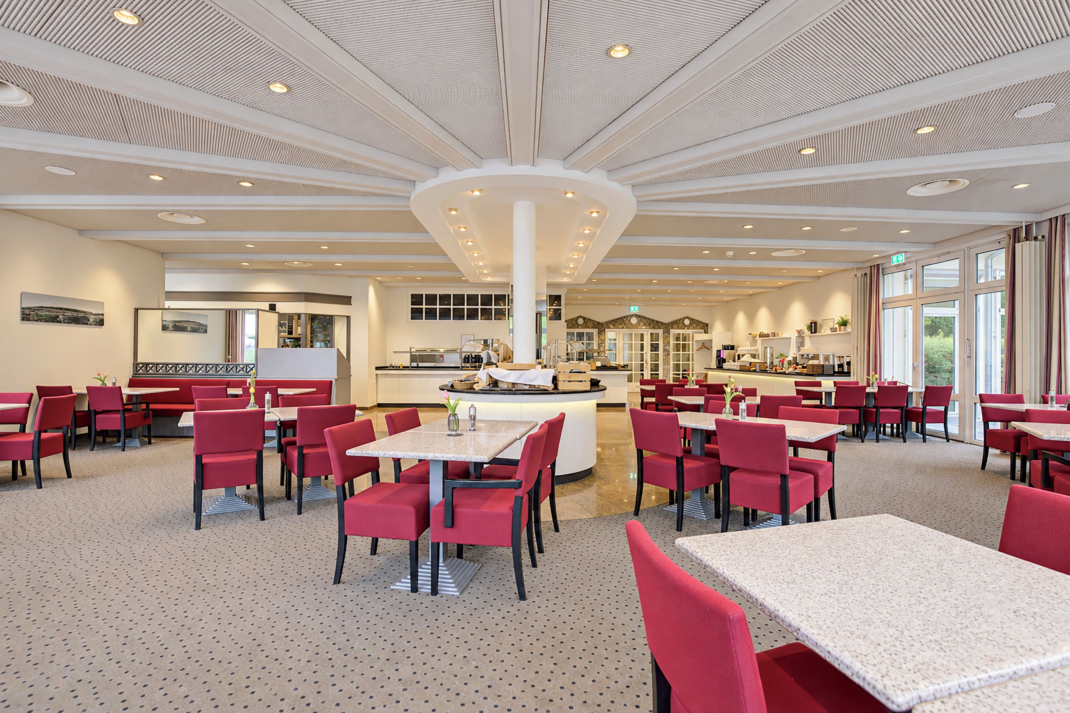A spacious dining area with multiple tables and chairs, a central island, and a modern ceiling design.