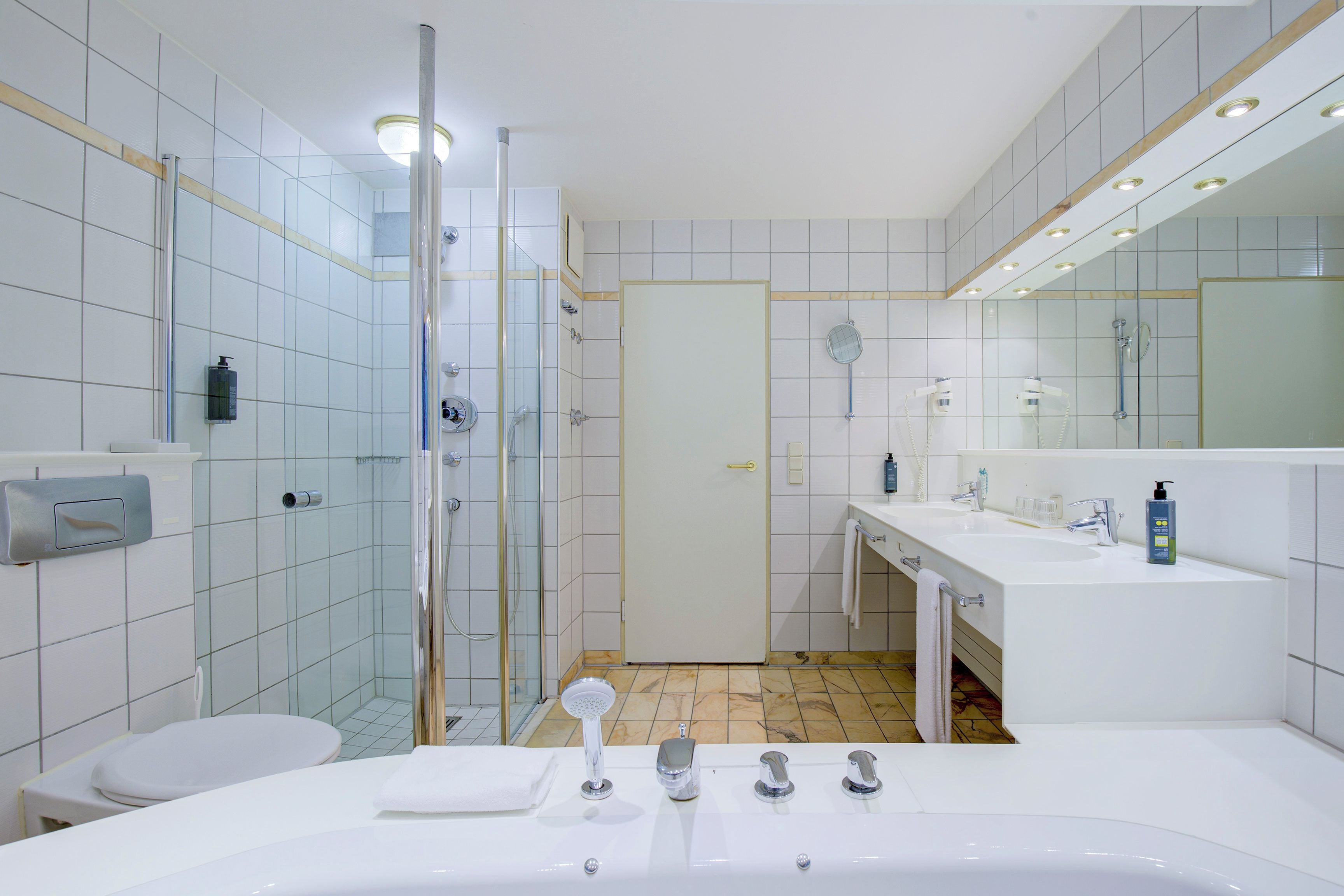 Ein modernes Badezimmer mit einer gläsernen Duschkabine, einer großzügigen Badewanne und einem Waschtisch mit zwei Becken.