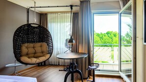 A modern room with a hanging chair, a small round table, and a view of a balcony. - Seminaris Hotel Bad Boll (Bad Boll)