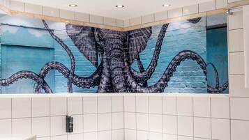 Ein Badezimmer mit einer großen Badewanne, weißen Fliesenwänden und einem Wandgemälde eines Oktopus.