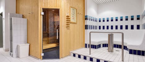 Una sala de sauna con puerta de madera, perchero y banco.