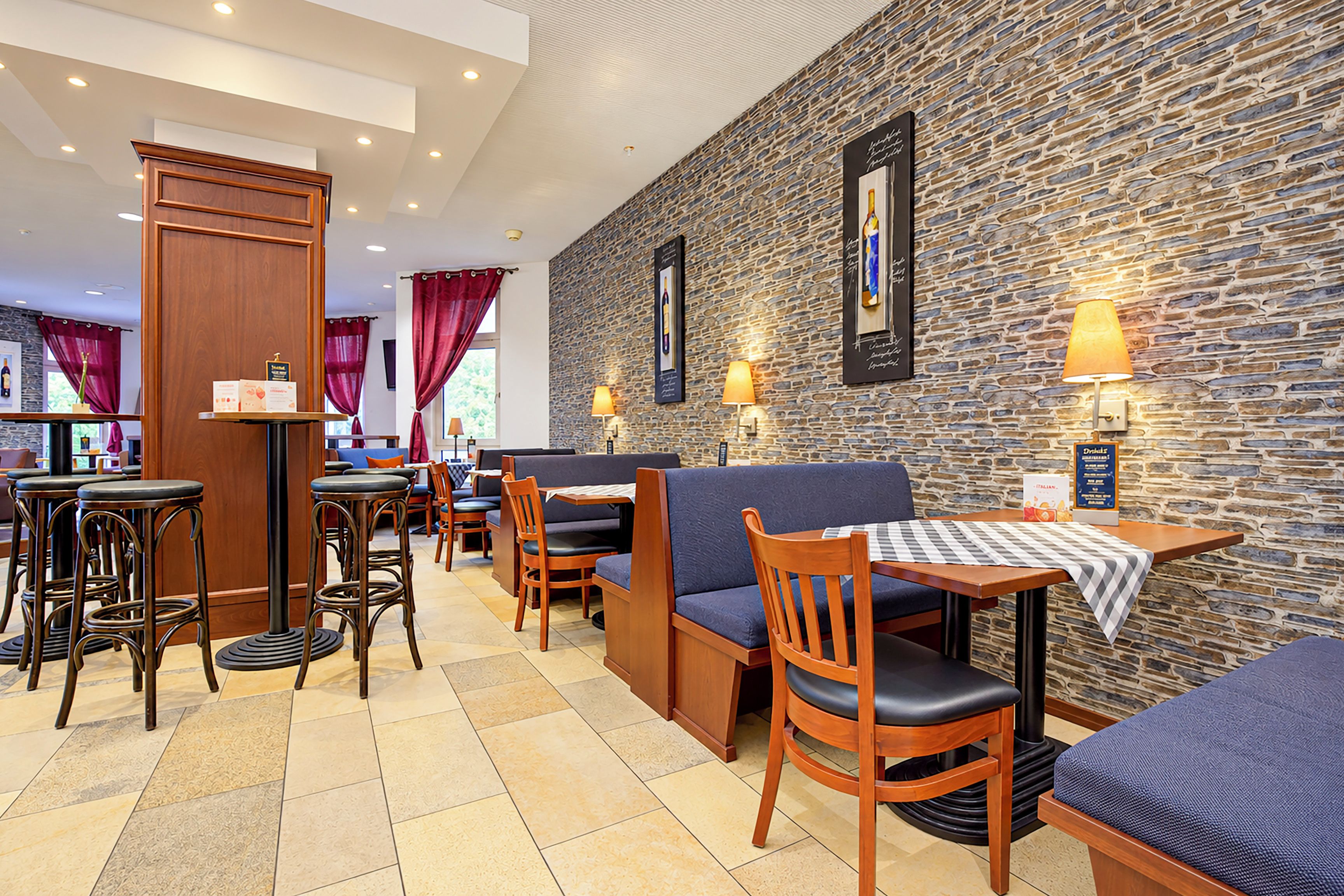 Interior de restaurante con paredes de piedra, muebles de madera y lámparas de mesa.