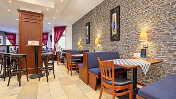 Interior de restaurante con paredes de piedra, muebles de madera y lámparas de mesa.