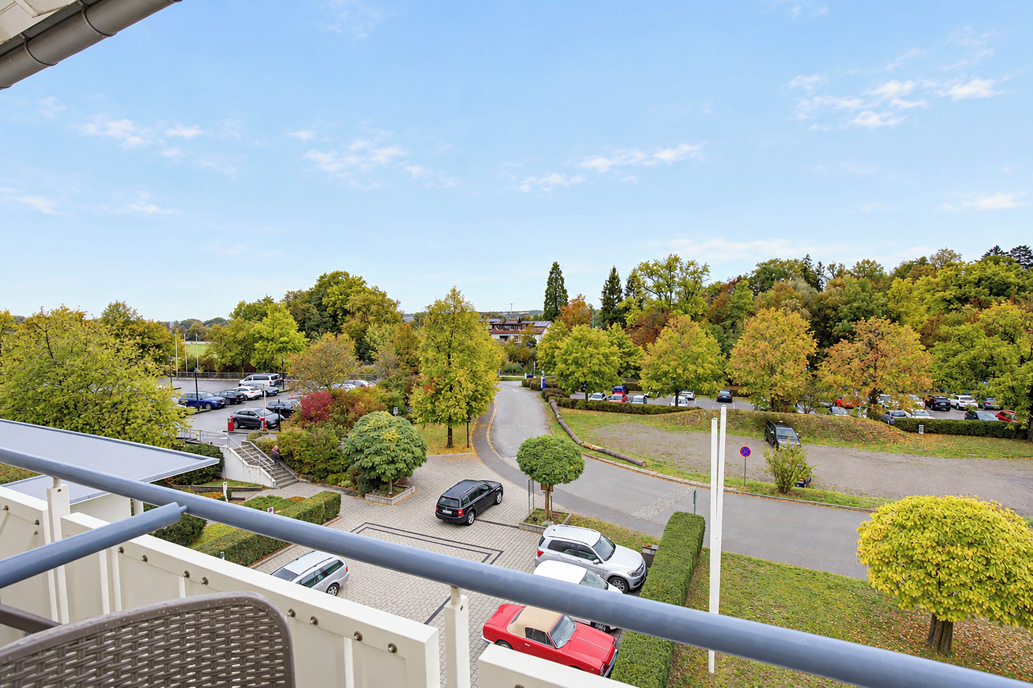 Ein Wohngebiet mit freiem Blick auf einen Parkplatz, Bäume und eine Straße.