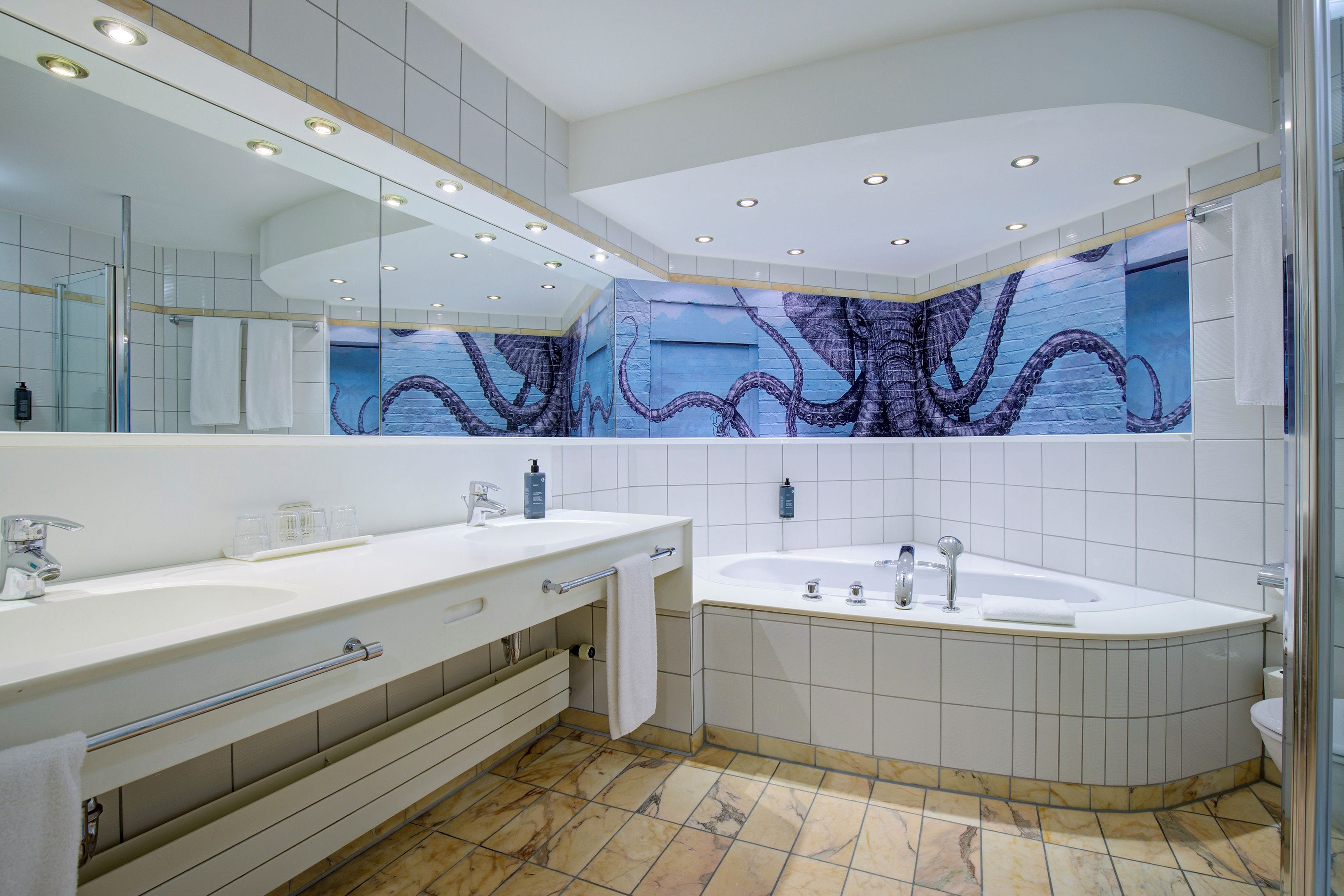 Un baño moderno con un espejo grande, lavamanos doble y bañera.