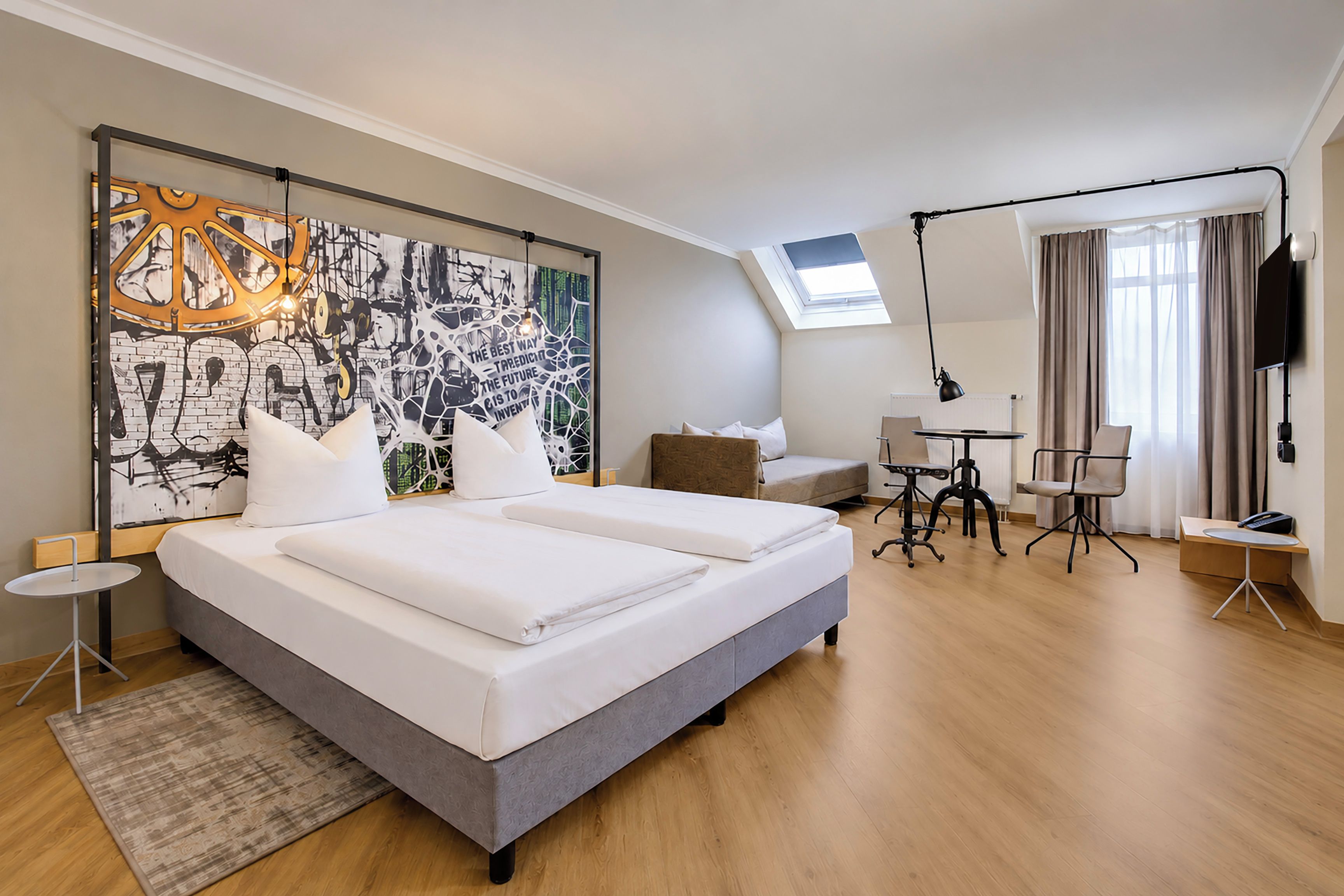 A hotel room with a large bed, a desk, a chair, a TV, and a window.