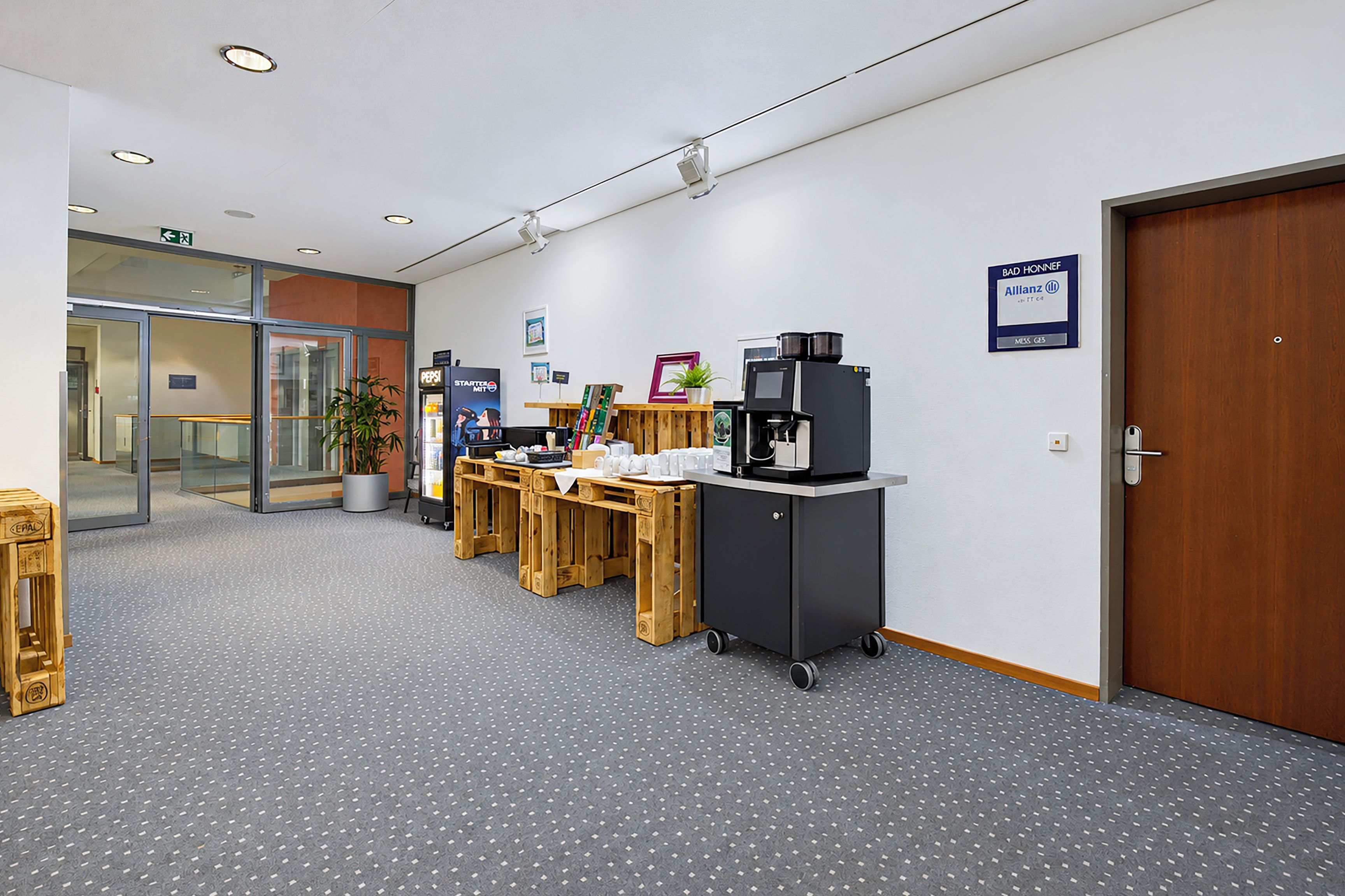 Ein modernes Interieur mit einer Rezeption, einer Kaffeemaschine und einer Tür mit der Aufschrift 'BAD HONNEF'.