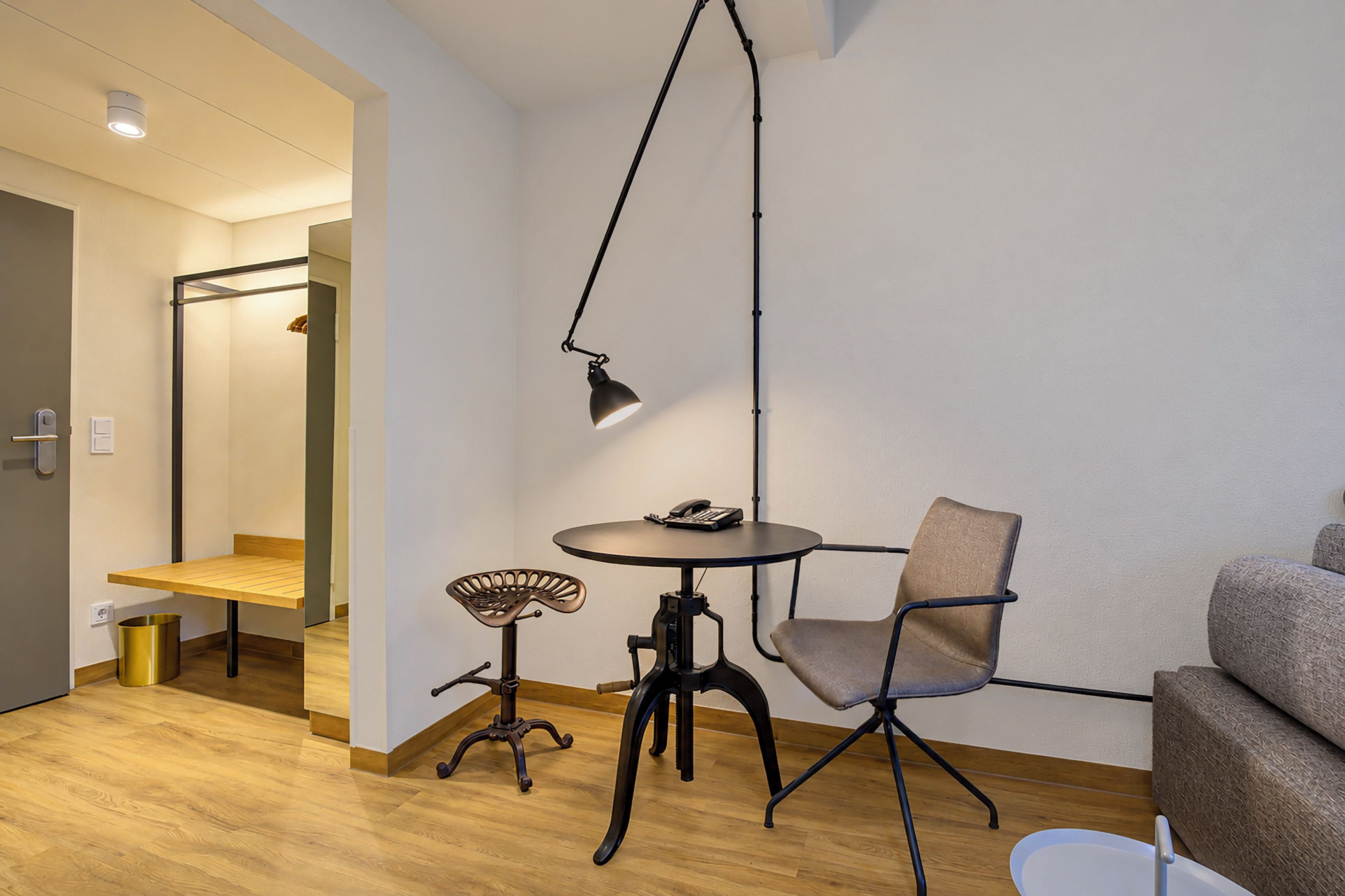 Ein modernes Zimmer mit einem runden Tisch, einem Stuhl, einem kleinen Hocker und einer Pendelleuchte.