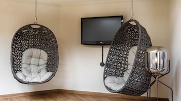 Une pièce avec deux fauteuils suspendus, un téléviseur à écran plat et une lampe sur pied.