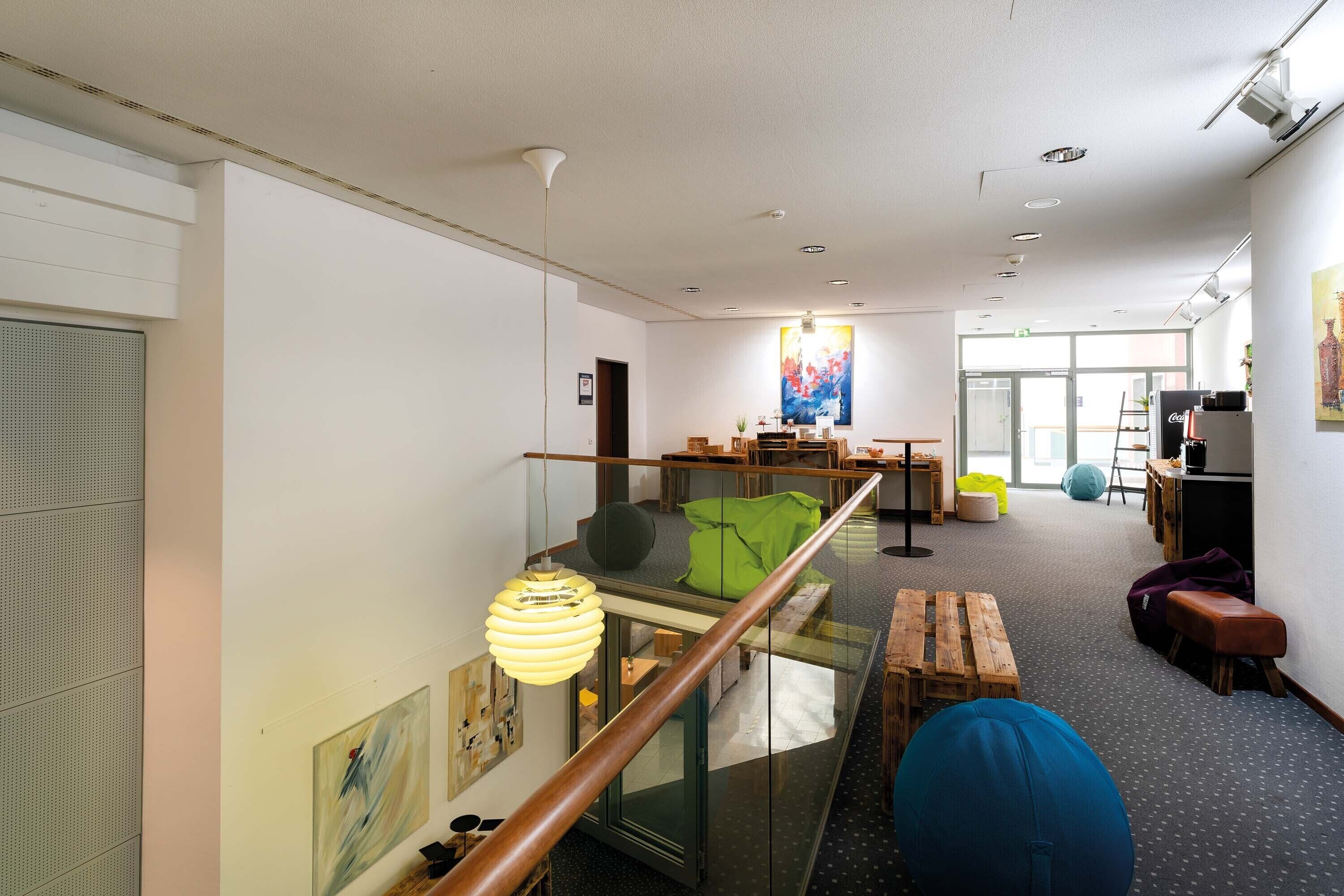 Un intérieur moderne avec une balustrade en verre, des meubles en bois et des œuvres d’art accrochées aux murs.