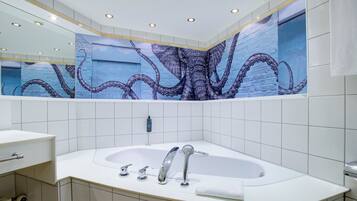 Une salle de bain moderne avec une grande baignoire, un miroir et une fresque murale représentant des tentacules de poulpe.