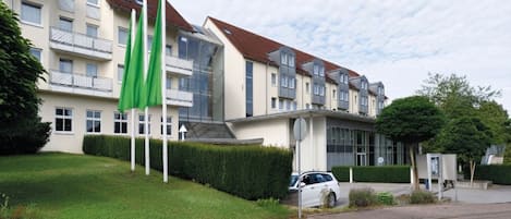 A multi-story residential building with a modern architectural design, featuring balconies and a well-maintained lawn.