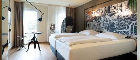 Une chambre d’hôtel moderne avec un grand lit, un bureau, un fauteuil suspendu et une fresque murale.