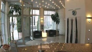 A modern hotel lobby with a curved ceiling, large windows, and a seating area with a sofa and coffee table. - Alfa Hotel (Karlsruhe)