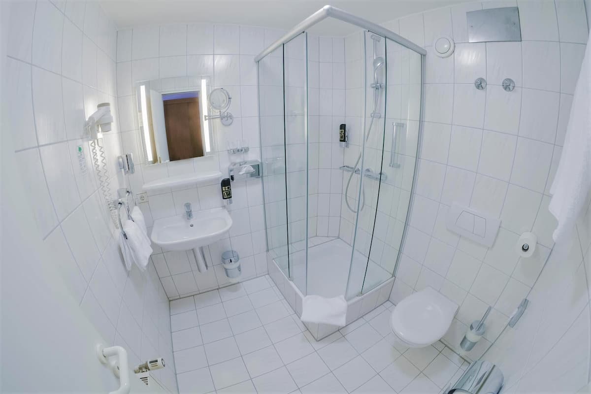 A modern bathroom with a glass-enclosed shower, a sink, and a toilet.