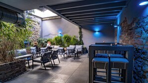 An outdoor patio with seating and a bar area, stone walls, and potted plants. - Alfa Hotel (Karlsruhe)