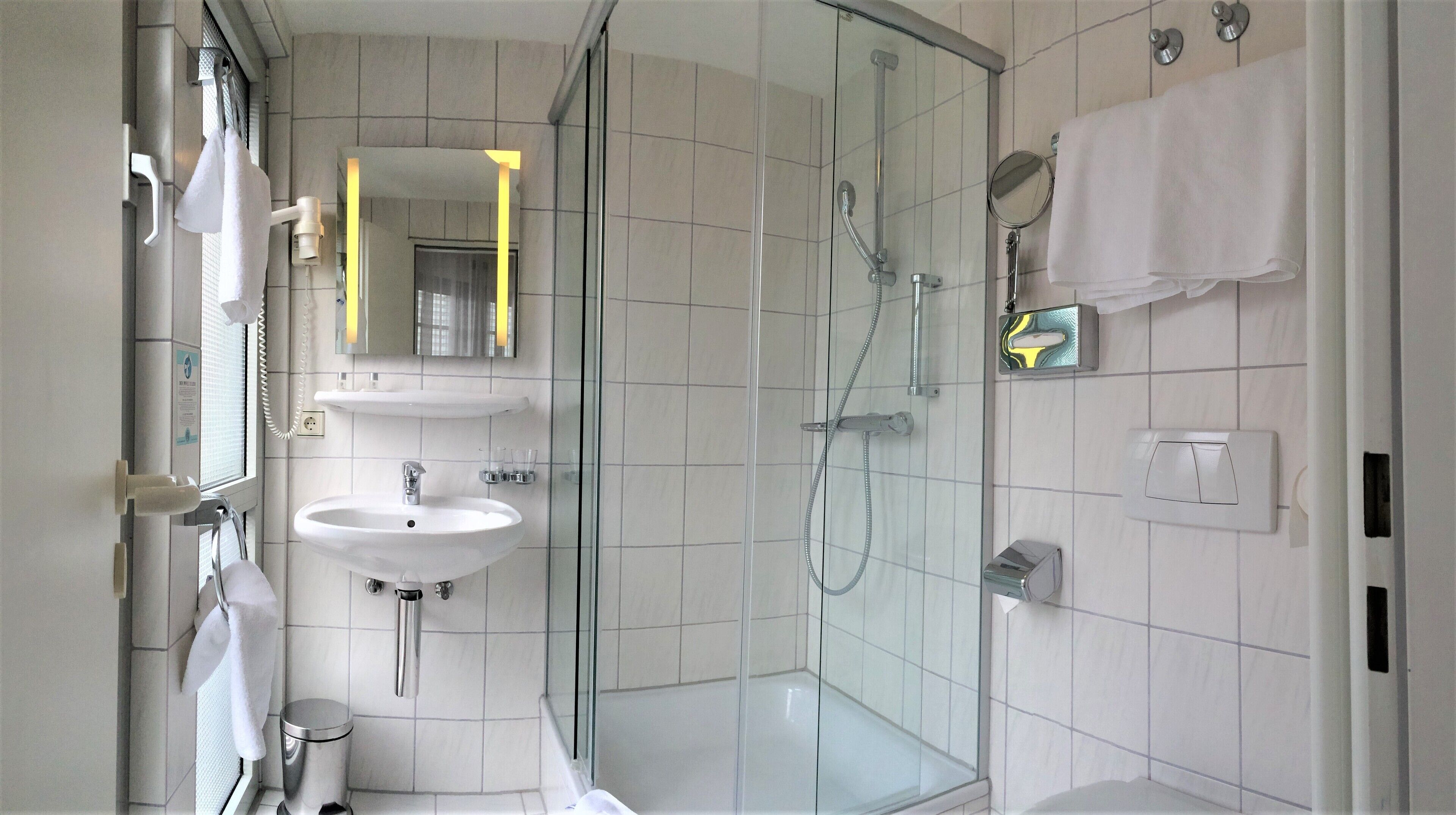 A modern bathroom with a glass-enclosed shower, a sink, and a mirror.