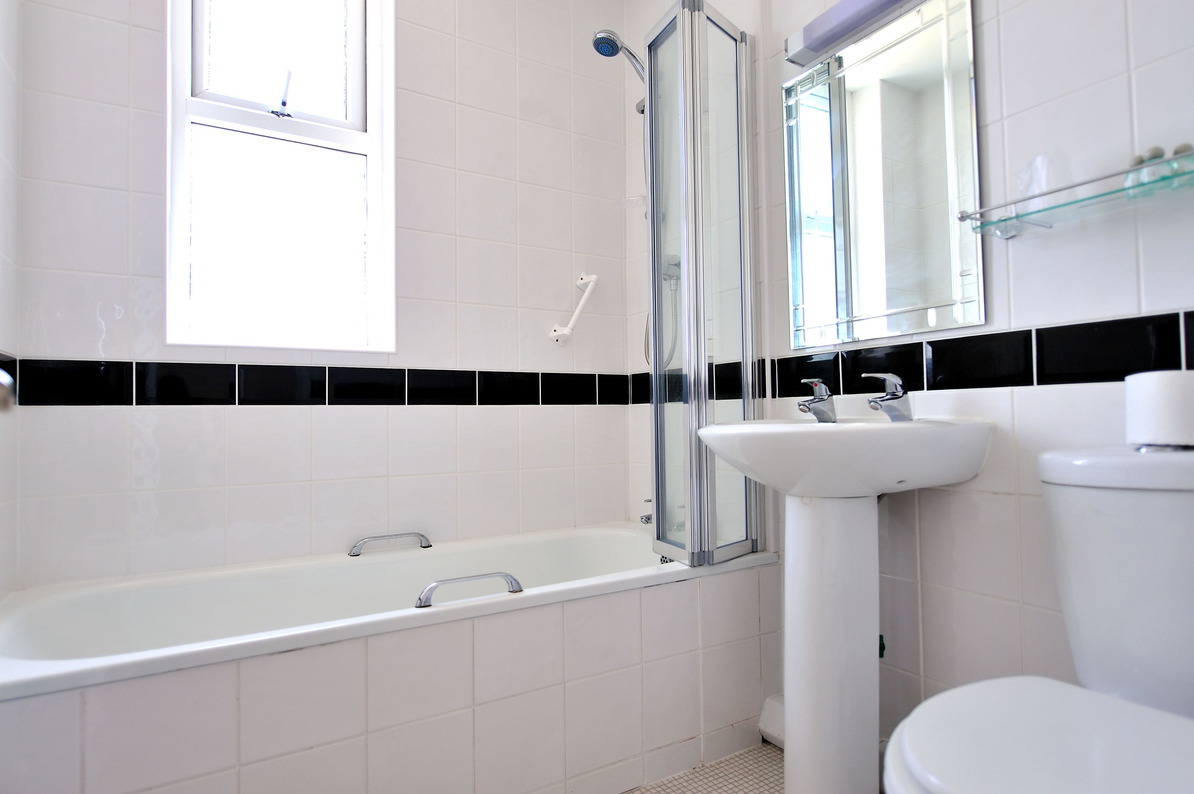 Un baño moderno con bañera, ducha con mampara de vidrio, lavabo e inodoro.