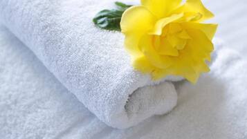 A neatly folded white towel with a yellow flower.