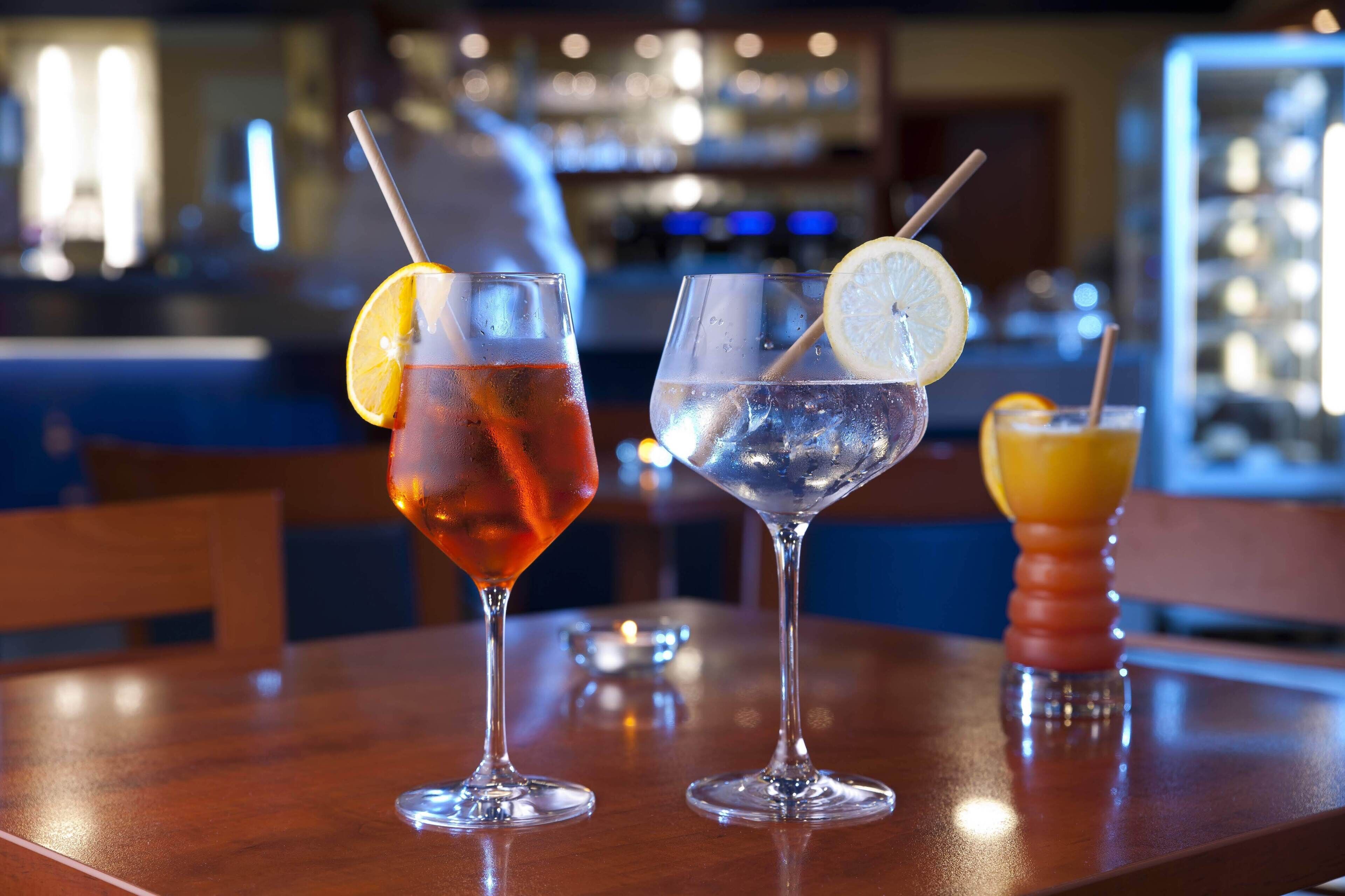 Tres bebidas sobre una mesa de bar, con un fondo desenfocado de una zona de bar.