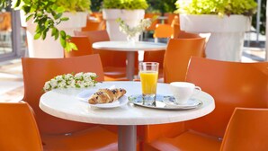 A round table with a croissant, a glass of orange juice, and a white cup on a tray. - Hotel Vesna (Šoštanj)