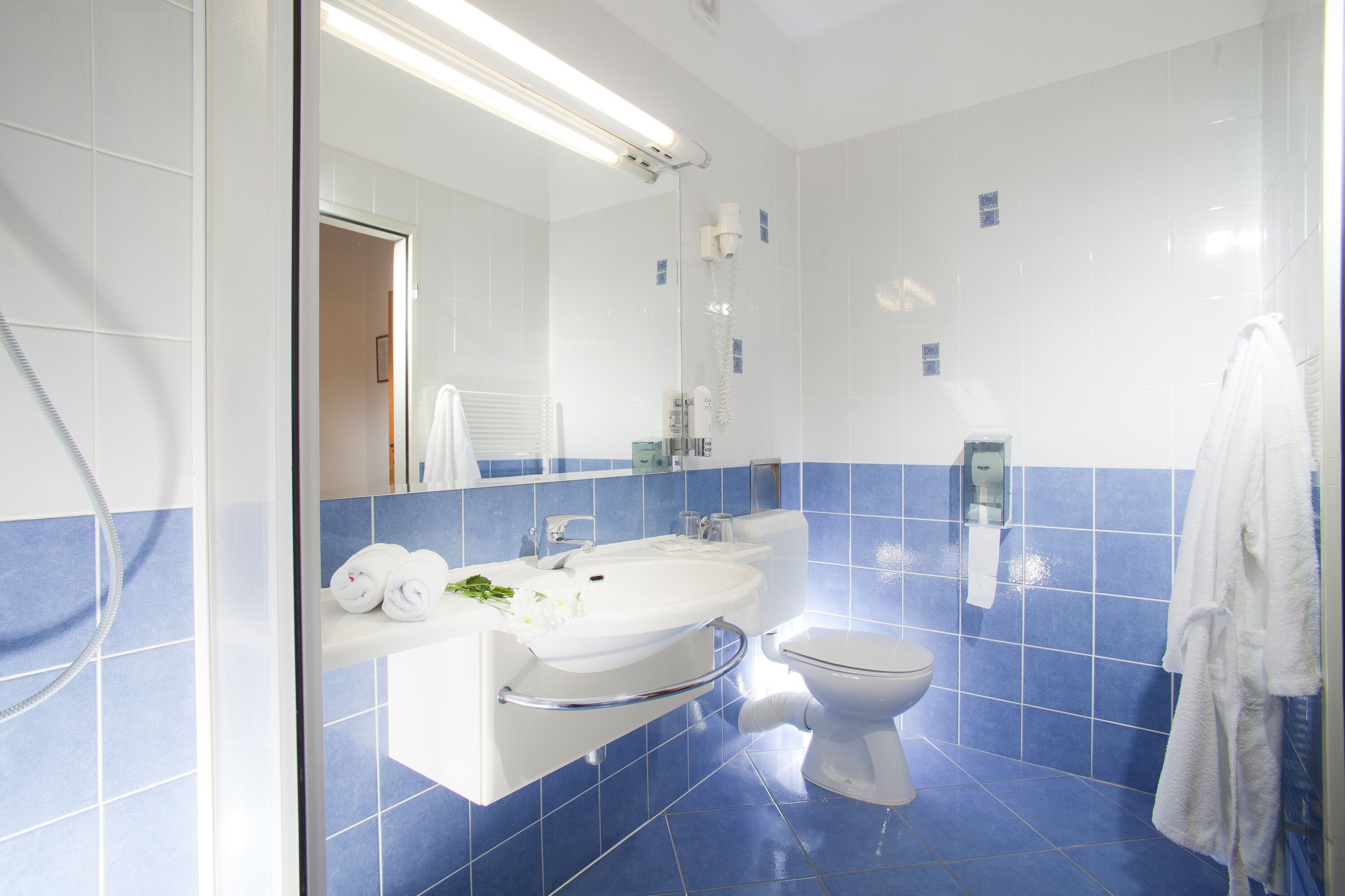 A modern bathroom with a white sink, a toilet, and a shower area.