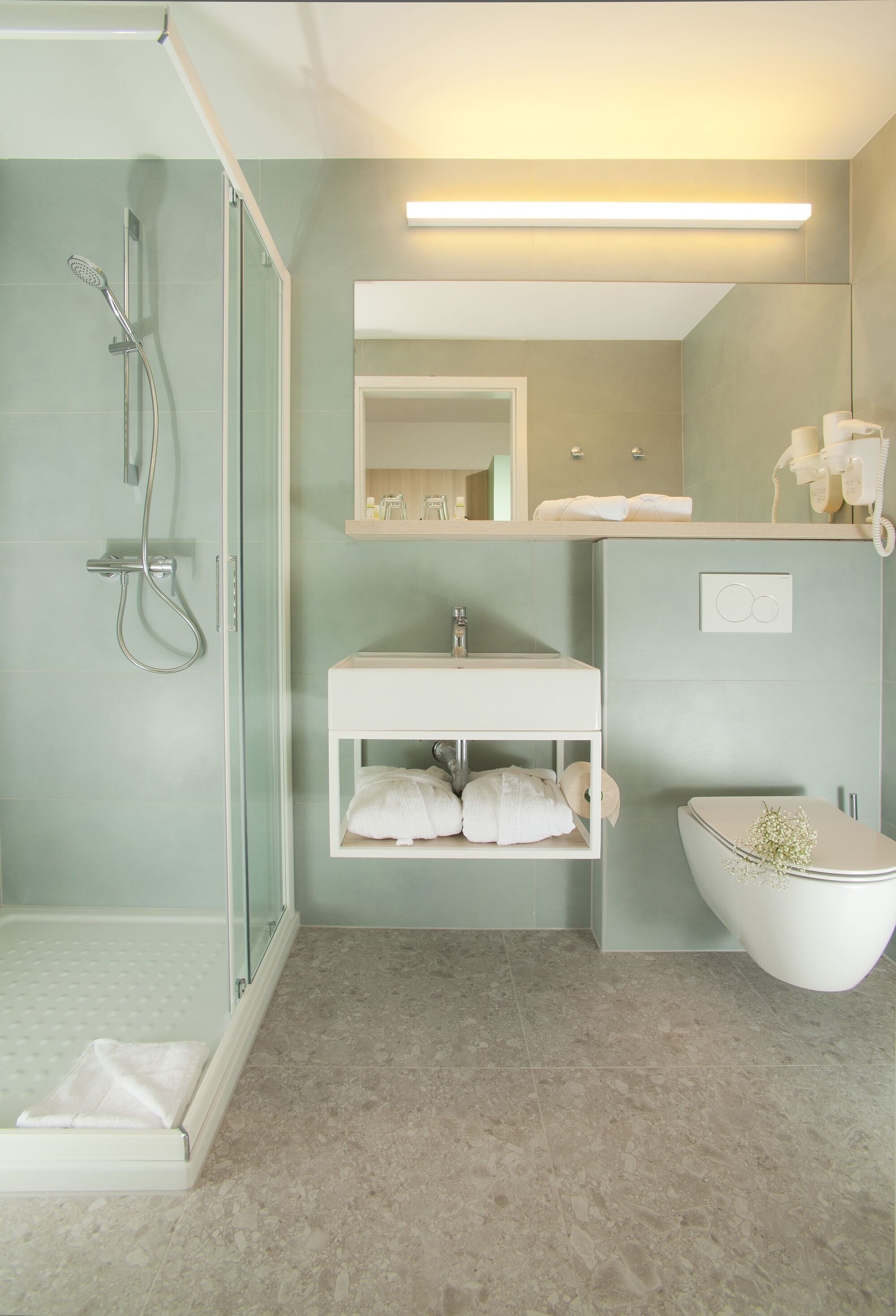 A modern bathroom with a glass-enclosed shower, a white sink, and a toilet.