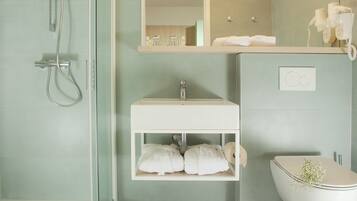 A modern bathroom with a glass-enclosed shower, a white sink, and a toilet.