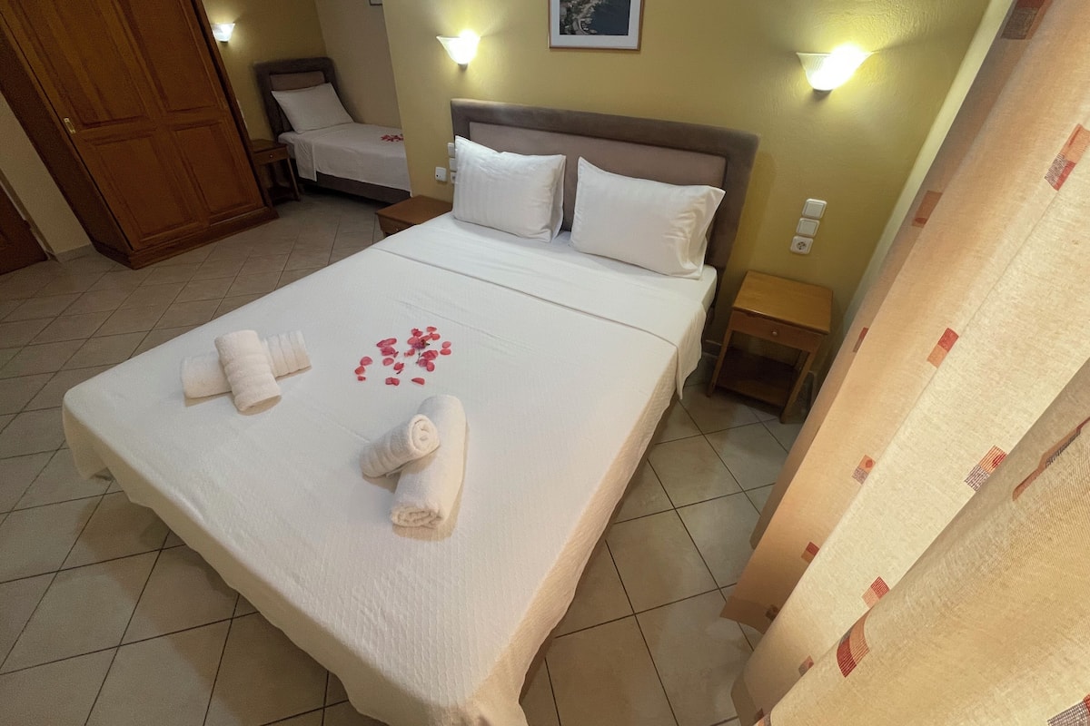 A hotel room with a large bed, two bedside tables, and a wooden door.