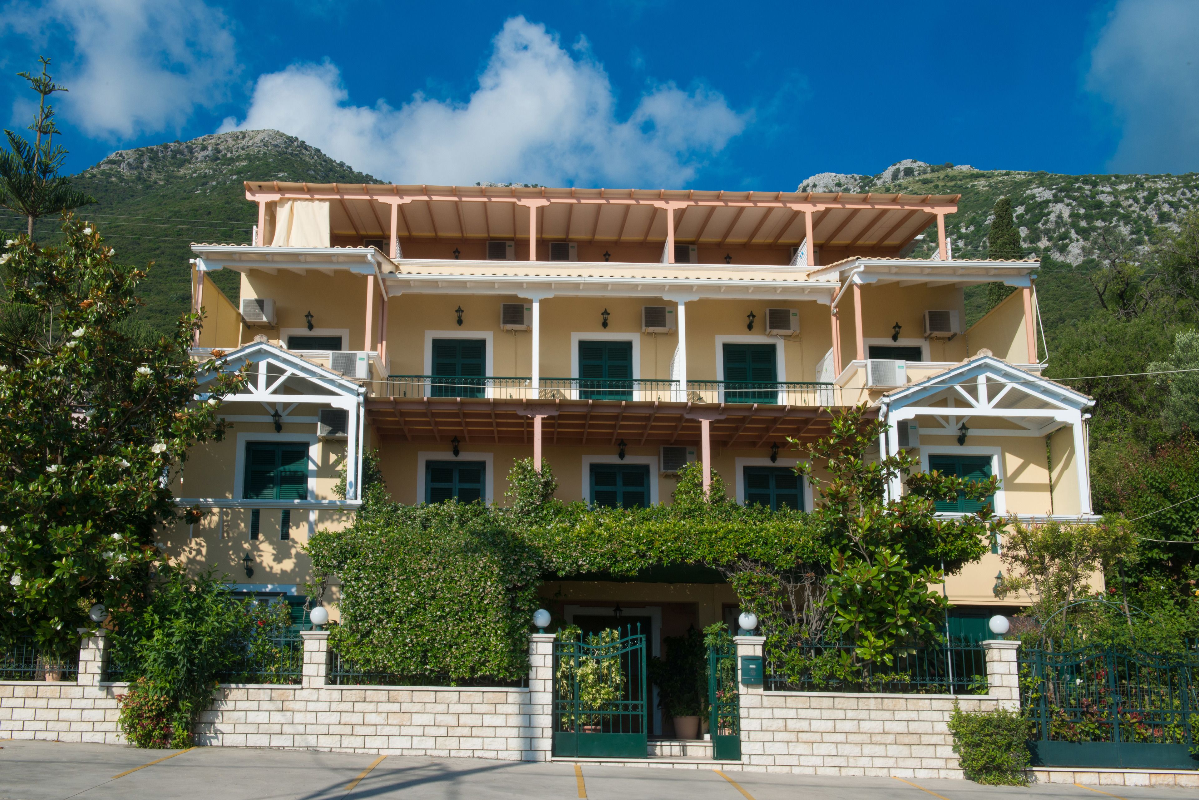 A two-story building with a balcony, a gate, and a mountain in the background.